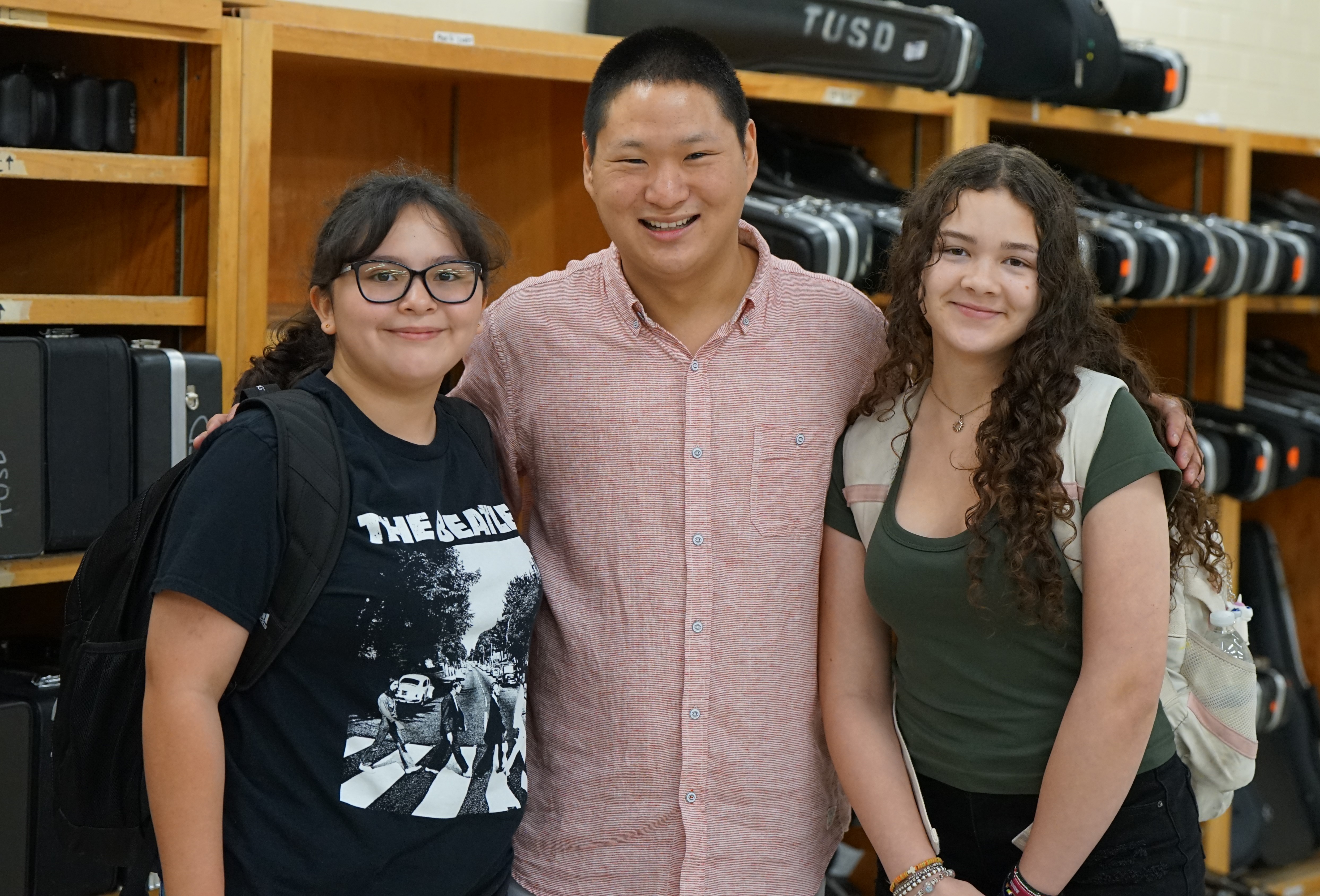 A teacher poses with two of his students in the band room