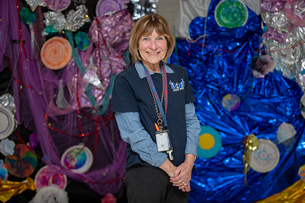 A woman in a blue shirt smiles in her classroom